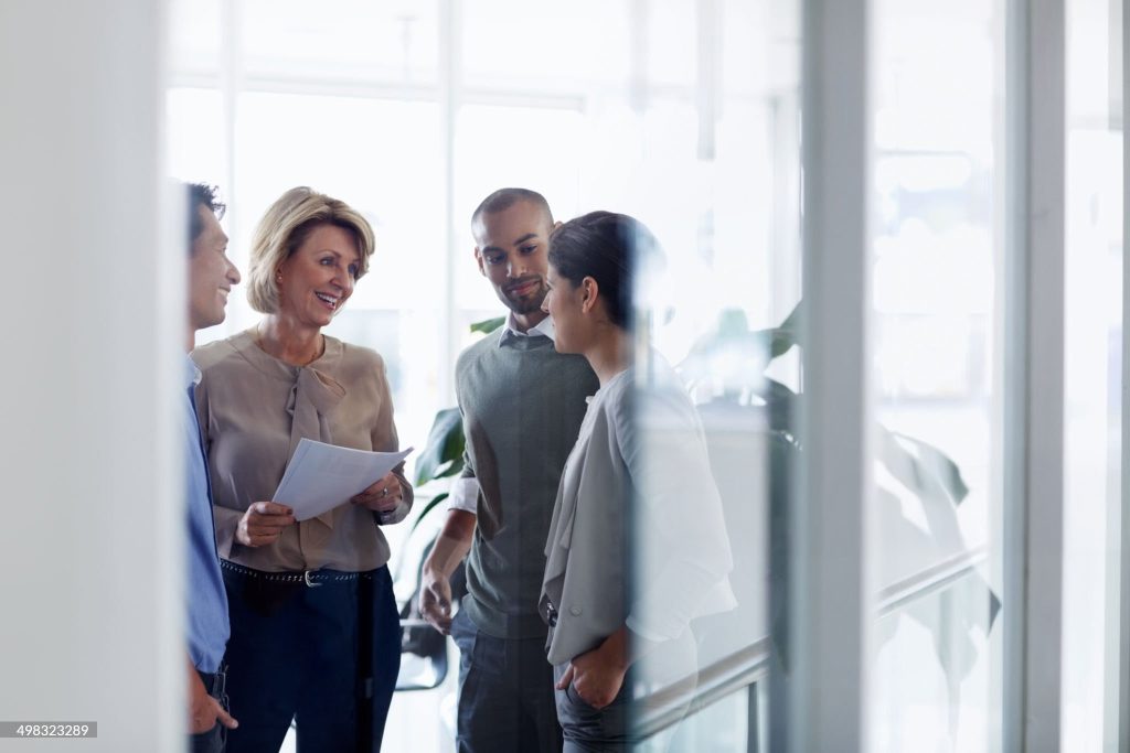 Smiling businesswoman discussing over document with colleagues in office
